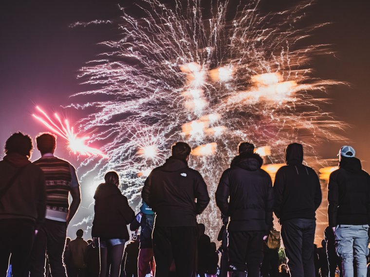 Public de dos regardant un bouquet de feu d’artifice doré